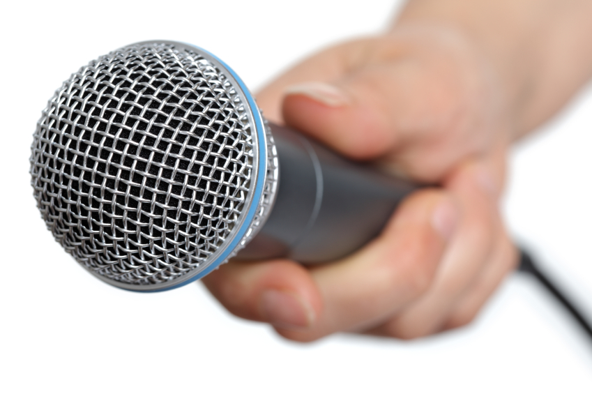 Womans hand holding a microphone conducting an interview